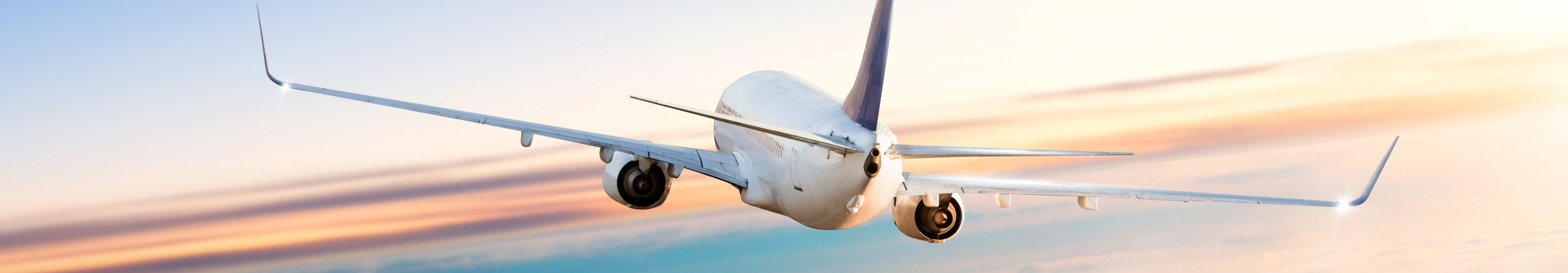 Flugzeug fliegt über Wolken bei dramatischem Sonnenuntergang