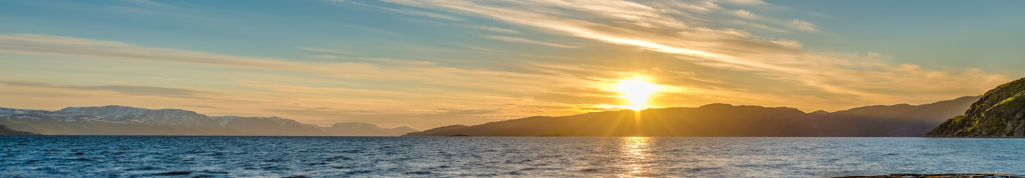 Sonnenuntergang am Meer mit Bergen im Hintergrund