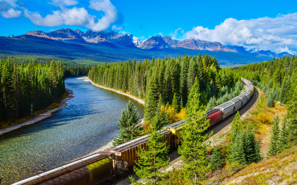 Langer Güterzug entlang des Bow River in den Kanadischen Rocky Mountains, Banff Nationalpark, Kanadische Rocky Mountains, Kanada.