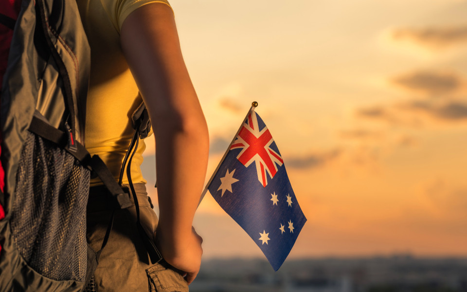 Frau mit Rucksack auf dem Rücken und Australien Fahne in der Hand