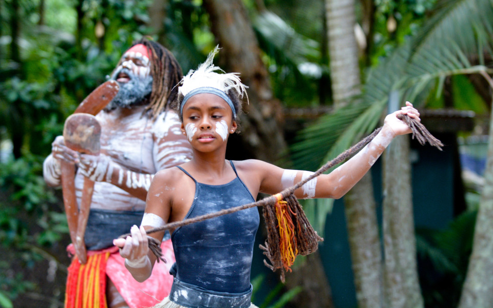 Junge erwachsene indigene Australierin tanzt in traditionellem Gewand. 