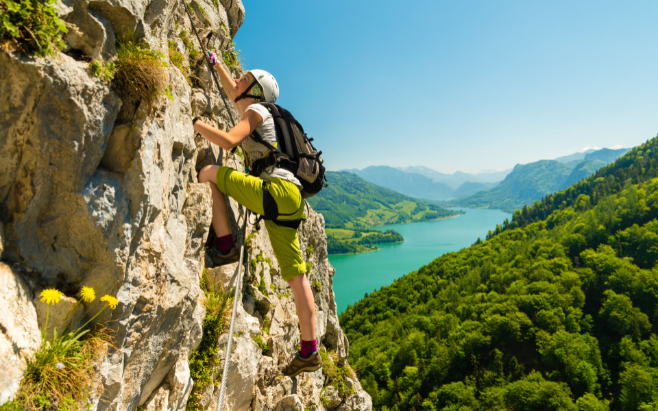 Junges Mädchen klettert Drachenwand-Klettersteig über dem malerischen Mondsee, Österreich 