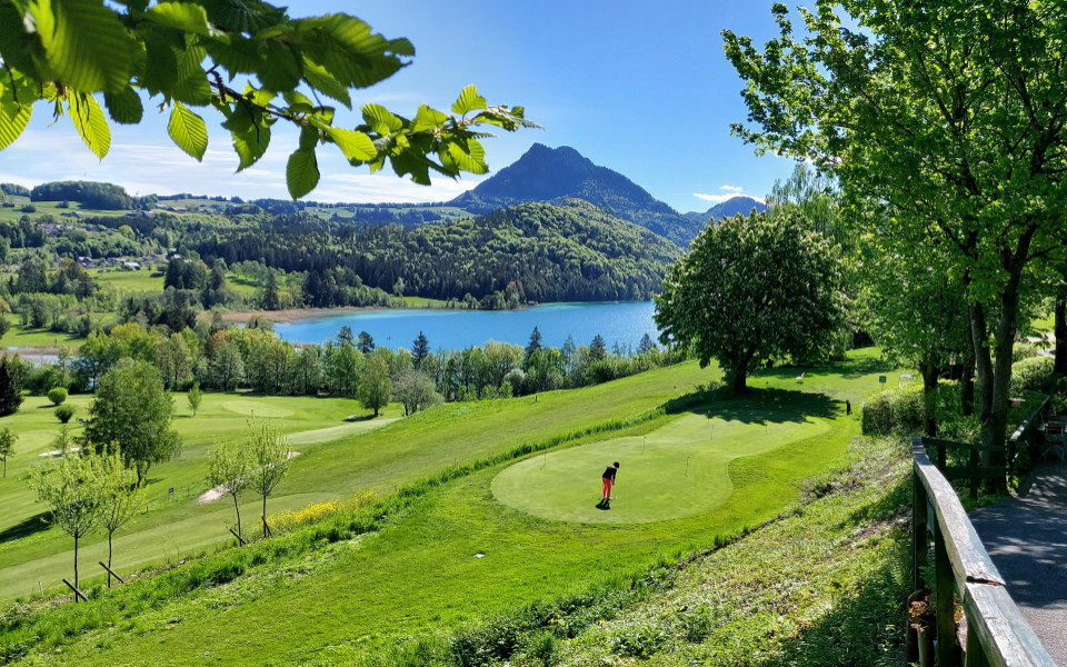 Person auf dem Golfplatz Schloss Fuschl in Österreich bei sonnigem Wetter mit dem Fuschlsee im Hintergrund 