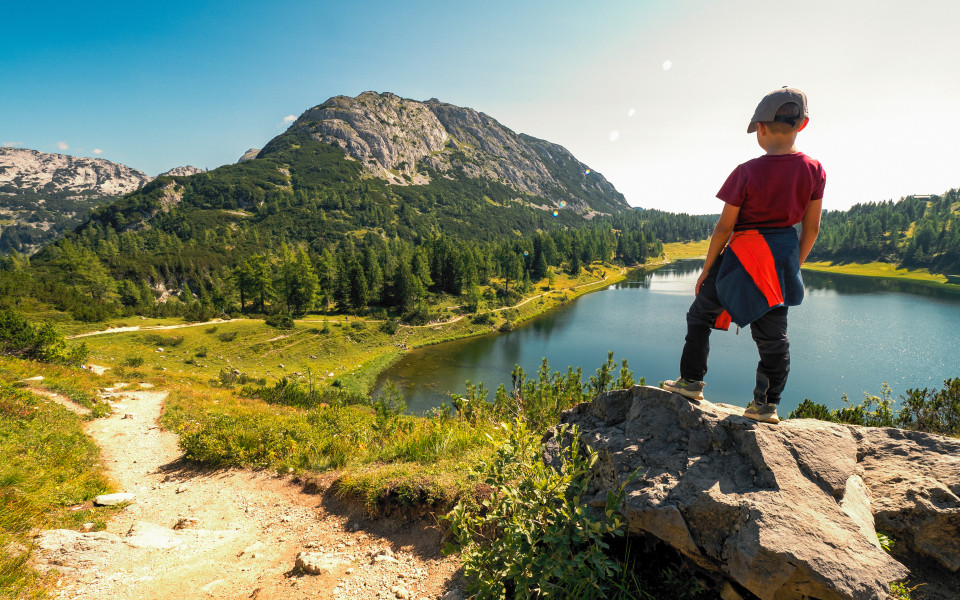 Wanderjunge steht hoch über dem Großsee mit dem Traweng im Hintergrund, Tauplitzalm, Tauplitz, Ausseer Land, Österreich