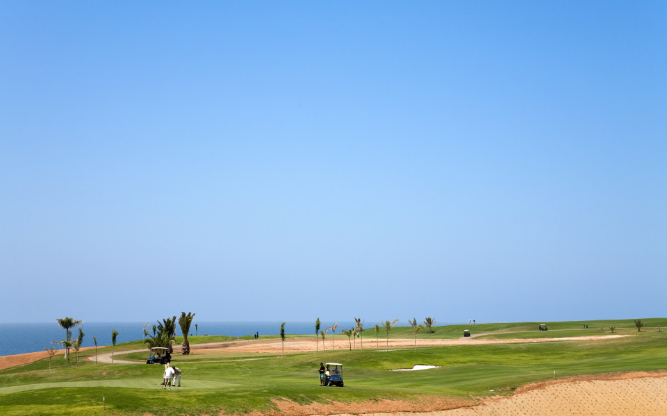 Grüner Golfplatz auf Gran Canaria mit Golfern und Caddy bei strahlend blauem Himmel