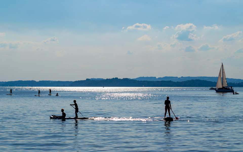 Segler und Stand-up-Paddler am Chiemsee mit Blick auf die Inseln 